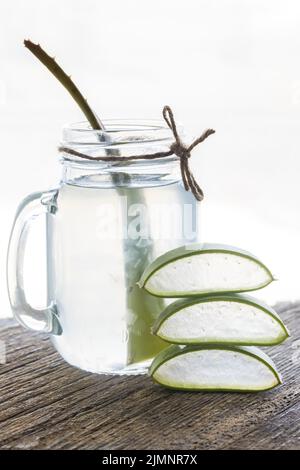 Aloe Vera Saft mit Aloe-Scheiben vor dem Fenster. Stockfoto