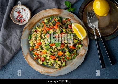 Tabbouleh Salat mit Quinoa. Östliche Speisen mit Gemüse mischen sich auf dunklem Tisch Stockfoto