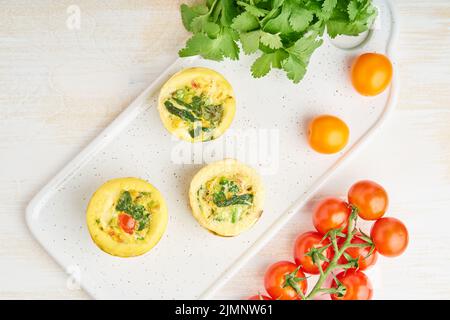 Eiermuffins, Paleo, Keto-Diät. Omelette mit Spinat, Gemüse, Tomaten Stockfoto