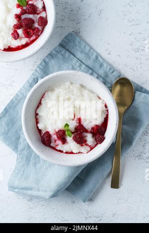 Reispudding. Veganes Kokos-Diät-Frühstück mit Kokosmilch, Himbeere, skandinavischem Minimalismus Stockfoto