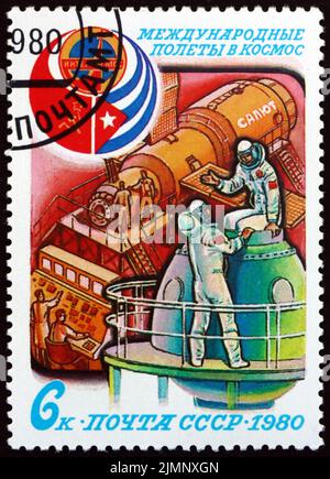 RUSSLAND - UM 1980: Eine in Russland gedruckte Briefmarke zeigt Kosmonauten-Training, Interkosmos-Emblem und Flaggen der UdSSR und Kubas, sowjetisch-kubanischer Kooperative Spac Stockfoto