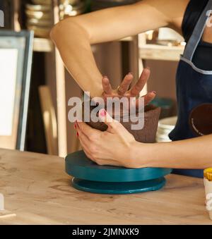 Frau, die Keramik anstellt, Hände in der Nähe, konzentriert sich auf Töpfer, Palmen mit Keramik Stockfoto