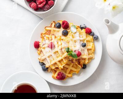 Belgische Waffeln mit Himbeeren, Blaubeeren, Quark und Tee, Draufsicht. Gesund hausgemacht Stockfoto