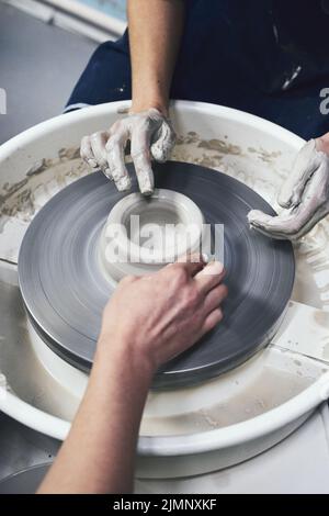 Frau, die Keramik auf dem Rad anstellt, Hände in der Nähe. Konzept für freiberufliche Frauen Stockfoto