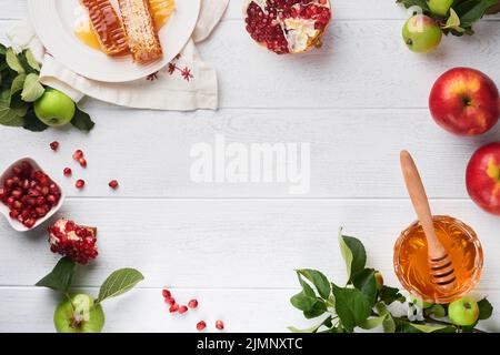 Rosh Hashanah. Honigglas, Honigwabe, Apfel und Granatapfel auf weißem Holz alten rustikalen Hintergrund Tisch. Grußkarte zum jüdischen Neujahrsfest. Rosh Ha Stockfoto