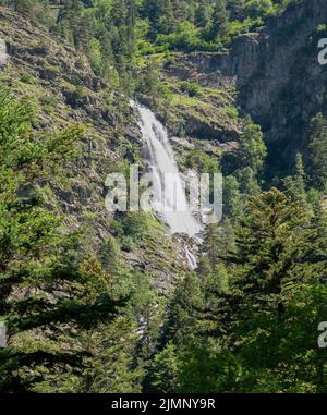 Hoher Wasserfall am Berg inmitten von Wäldern und Felsvorsprüngen Stockfoto