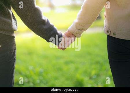 Ein Mann neben der Frau, ein Mann und ein Mädchen stehen nahe, berühren sich und halten die Hände. Das Konzept der ersten Teenager-Liebe. B Stockfoto