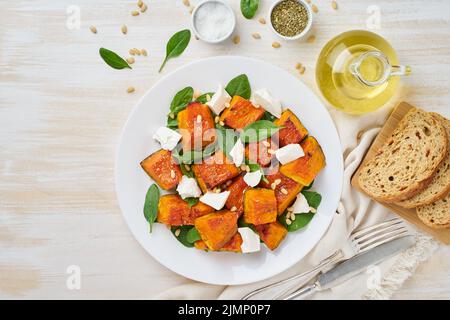 Salat mit geröstetem Kürbis, Fetakäse, Spinat, Nüssen mit Honig und Gewürzen, Draufsicht Stockfoto