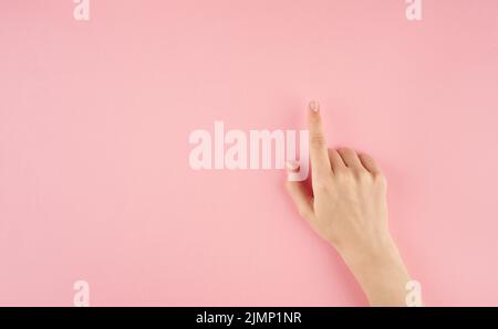 Schöne Frau Hand berühren oder zeigen auf etwas auf rosa Hintergrund mit Copy Space Draufsicht Stockfoto