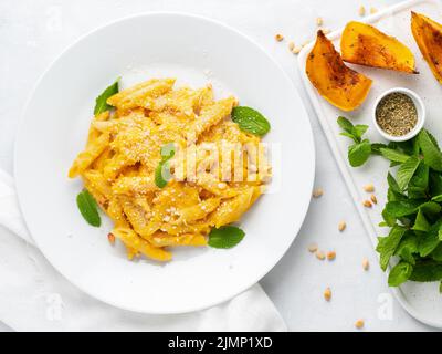Kürbis-Pasta-Penne mit cremiger Sauce gebackenem Squash auf weißem Hintergrund, Draufsicht Stockfoto