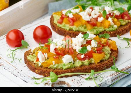 Avocado-Toast mit Feta und Tomaten, mit Ricotta, Nahaufnahme, geröstet Stockfoto