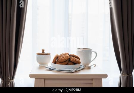 Frühstück mit Kaffee und Keksen auf einem Holztisch im Schlafzimmer Stockfoto