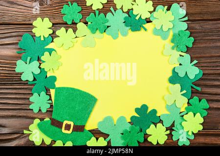 Happy St. Patrick's Grußkarte mockup von handgefertigten Filzhut und Shamrock clover Blätter auf hölzernen Tisch Stockfoto