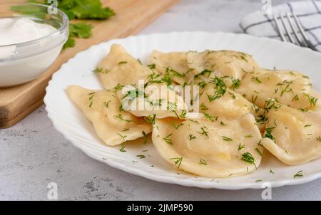 Traditionelles Gericht der slawischen Küche. Mit Kartoffeln gefüllter Varenyky auf einem weißen Teller Stockfoto