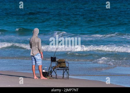 Ein Mann schaut auf die Brandung, bevor er an einem Strand in Pensacola Beach, Florida, angeln kann. Stockfoto