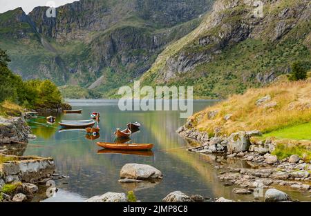 Die malerische Küste des Gebirgssees von Norwegen in der Nähe der Lofoten-Inseln, Fischerboote, die Hänge der Berge covere Stockfoto