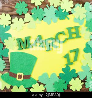 Happy St. Patrick's Grußkarte mockup von handgefertigten Filzhut und Shamrock clover Blätter auf hölzernen Tisch Stockfoto