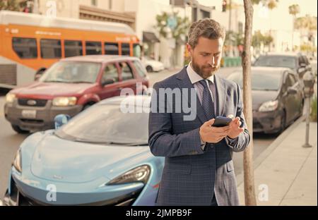 Autoversicherung. Geschäftsleute mieten ein Luxus-Auto per Telefon Stockfoto