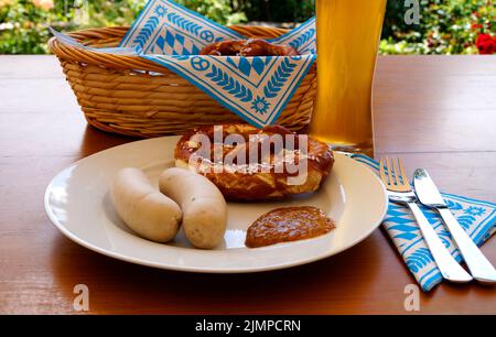 Ein traditionelles bayerisches Gericht: Weißwürste, knackige, salzige Brezeln mit süßem Senf und deutschem Bier und ein Korb mit Prezeln Stockfoto