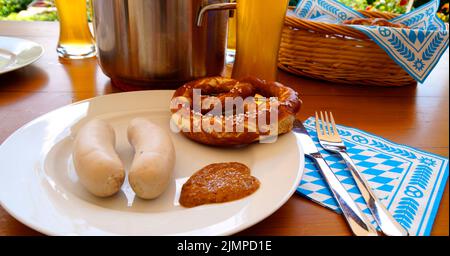 Ein traditionelles bayerisches Gericht: Weißwürste, knackige, salzige Brezeln mit süßem Senf und deutschem Bier und ein Korb mit Prezeln Stockfoto