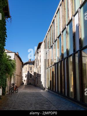 Blick auf eine gepflasterte Straße mit modernen hohen Glasgebäuden und mittelalterlichen Wohnhäusern Stockfoto