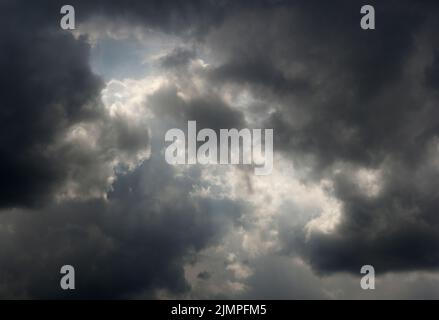 Dunkle Wolken sammeln sich mit einer leichten Lichtung Stockfoto