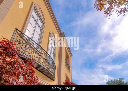 Schräg abgewinkelte Ansicht eines Hauses mit gelben Wänden und Metallfenstergeländern. Residenz in San Francisco, Kalifornien mit Ahornbäumen an der Vorderseite und Stockfoto