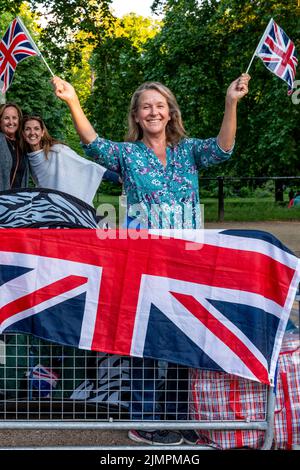 Eine Britin waves Union Flags vor der Queen's Birthday Parade, The Mall, London, Großbritannien. Stockfoto