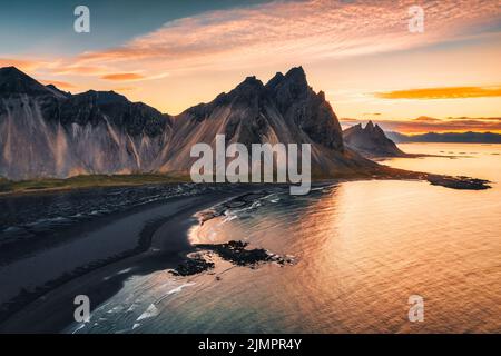 Luftaufnahme des wunderschönen Sonnenaufgangs über dem Vestrahorn-Berg und dem schwarzen Sandstrand im Atlantischen Ozean bei Stokksnes im Südosten Islands Stockfoto