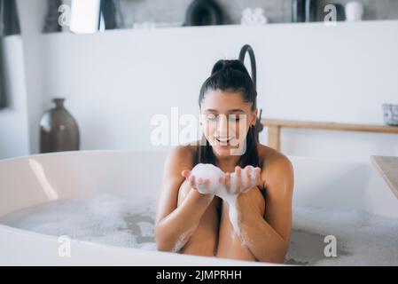 Die junge Frau genießt den Schaum beim Baden Stockfoto