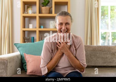 Porträt einer glücklichen kaukasischen älteren Frau, die zu Hause auf dem Sofa sitzt Stockfoto