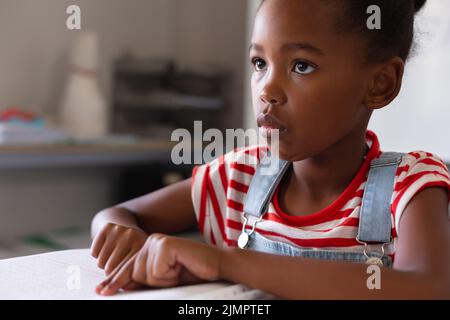 afroamerikanische Grundschülerin schaut weg, während sie im Unterricht an Braille-Büchern studiert Stockfoto