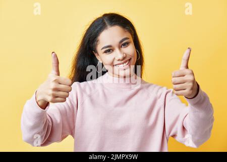 Lächelnde, hübsche Frau, die das Daumen hoch zeigt Stockfoto