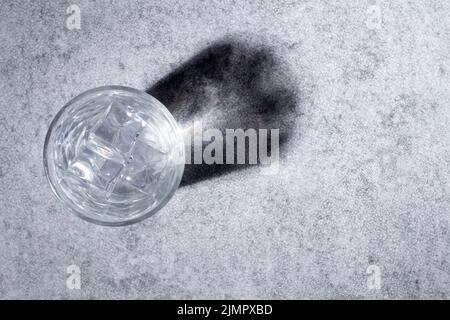 Ansicht von oben auf Glas mit Eiswürfeln und Wasser, das eine Reflexion projiziert Stockfoto