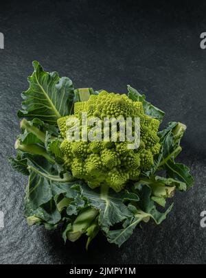 Romanesco Brokkoli Kopf auf einer dunklen Steinoberfläche, Kohl, Nahaufnahme, fibonacci-Sequenz, für diejenigen, die Mathematik lieben Stockfoto
