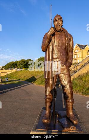 A High Tide in Short Wellies, eine Skulptur von Ray Lonsdale eines Fischers, die hoch und stolz auf der Promenade in Filey, North Yorkshire, steht. Stockfoto