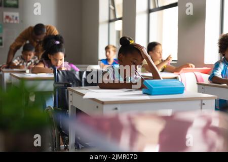 Multirassische Grundschüler, die im Klassenzimmer am Schreibtisch studieren Stockfoto