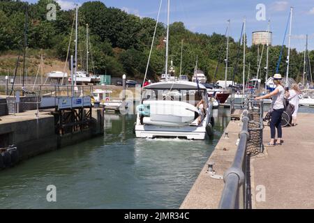 Shotley Marina an einem Sommertag in Suffolk mit einem Boot, das durch die Schleuse in die Marina fährt. Stockfoto