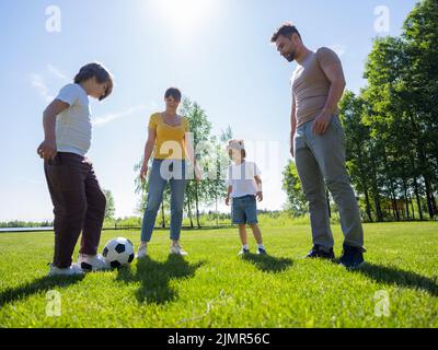 Glückliche Familie mit zwei Kindern spielt in ihrer Freizeit Fußball Stockfoto