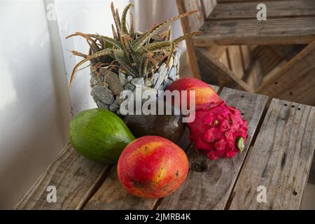 Mangos, Avocados, Drachenfrüchte und Aloe Pflanzen auf einem alten holzgrauen Plankentisch Stockfoto