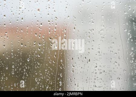 Regentropfen auf einer Fensterscheibe bei regnerischem Wetter Stockfoto