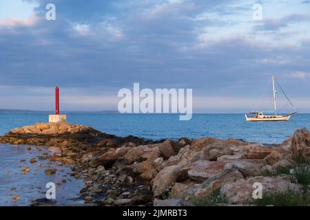 Leuchtturm und Segelboot badeten im Nachmittagslicht in Potamos Liopetri Fischerdorf, Mittelmeer, Zypern Stockfoto