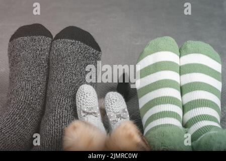 Die Beine einer Frau, eines Mannes und einer Katze in Socken in einem Zuhause. Stockfoto