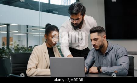 Arabischer Mann Trainer Corporate Trainer Chef Führer Lehrer Mentor Lehre Praktikanten Manager Mitarbeiter verwenden Online-Anwendung Software zeigt in Laptop Stockfoto