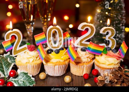 Cupcakes mit Neujahr Kerzen Weingläser und kleine Homosexuell Fahnen Dekorationen Stockfoto