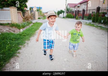 Zwei Brüder gehen und halten sich die Hände, Bruder liebt. Stockfoto