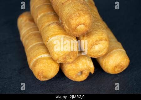 Tequenos. Ein Haufen frittierter gebackener Käsestäbchen auf dunklem Hintergrund. Venezolanischer Snack Stockfoto