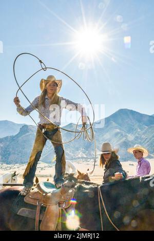 Cowgirl mit Lasso auf dem Pferd stehend. Vertikal Stockfoto