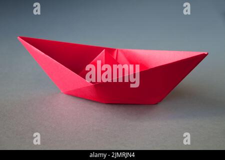 Rotes Papier Boot Origami isoliert auf einem grauen Hintergrund Stockfoto