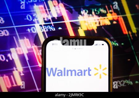 KONSKIE, POLEN - 07. August 2022: Smartphone mit Logo von Walmart Inc auf dem Hintergrund des Börsendiagramms Stockfoto